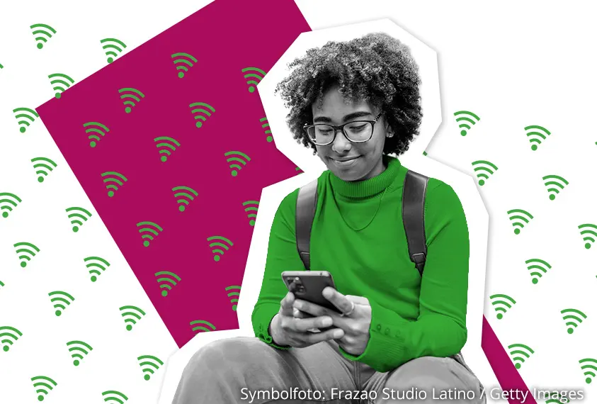Eine Person mit lockigem Haar und Brille schaut aufs Smartphone.