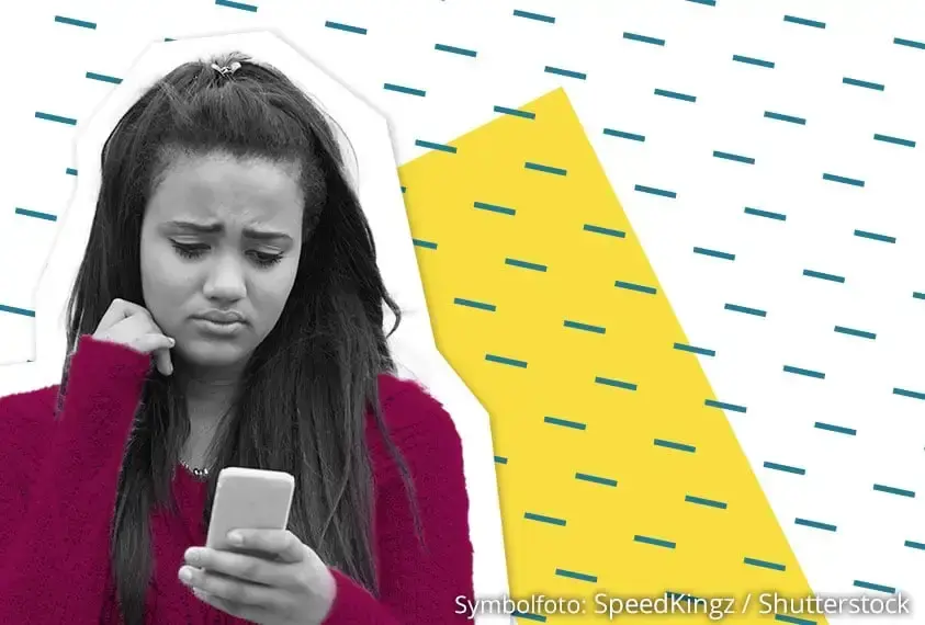 Junge Frau blickt besorgt auf ihr Handy &ndash; Symbol f&uuml;r Cybermobbing in sozialen Medien.