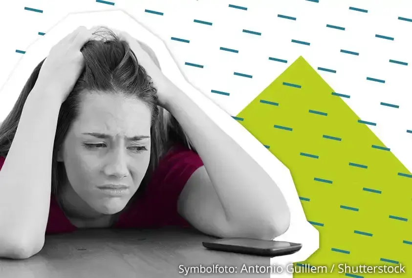 Verzweifelte Jugendliche schaut traurig auf ihr Smartphone &ndash; Darstellung von Online-Mobbing.