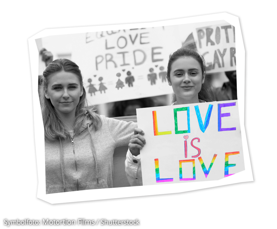 Zwei Mädchen mit einem Schild auf dem in Regenbogenfarben steht: Love is Love