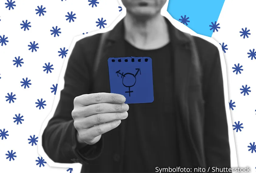 Eine Person zeigt eine Karte mit einem Genderzeichen in die Kamera